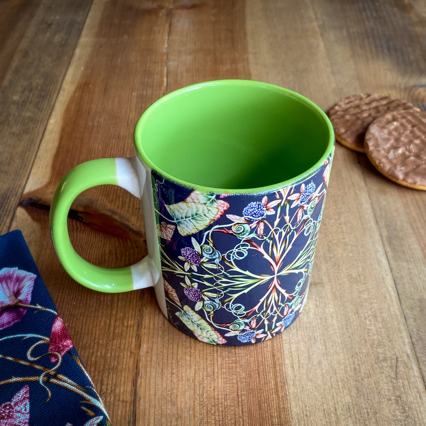 Green mug with floral pattern on a wooden surface. Illustrated by April Mawhinny