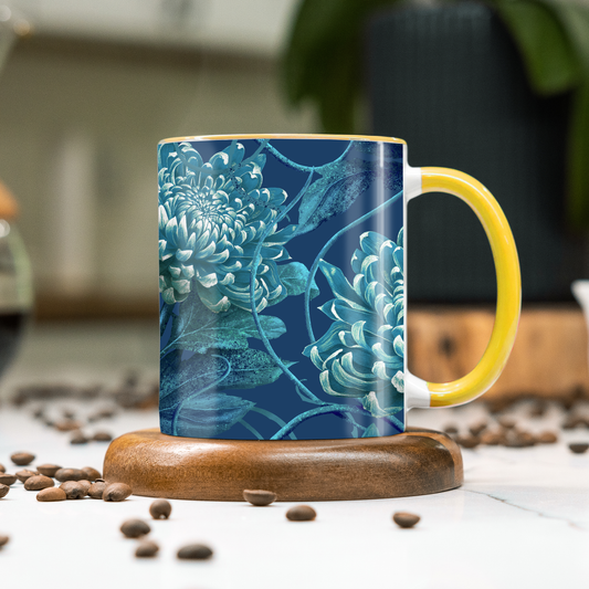 Mug with blue floral design and yellow handle on a wooden coaster with coffee beans around