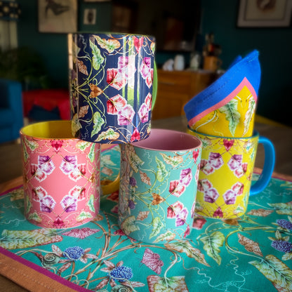 Colorful floral-patterned mugs on a table with a patterned tablecloth. April Mawhinney Illustration