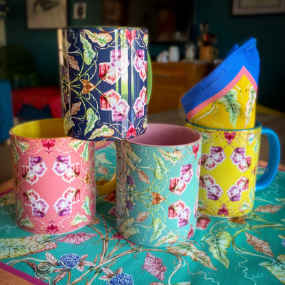 Colorful floral-patterned mugs on a table with a patterned tablecloth. April Mawhinney Illustration