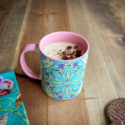 Decorative turqouise and pink mug with floral pattern on a wooden surface
